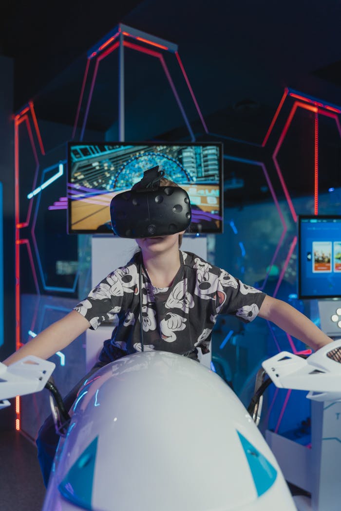 our-story Young boy immersed in virtual reality experience at an arcade, playing an electronic racing game.